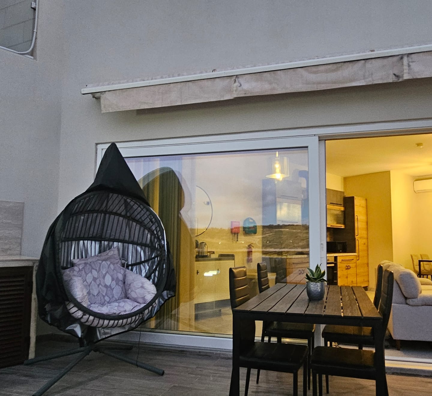 Outdoor dining table and hanging chair in the penthouse terrace lounge area