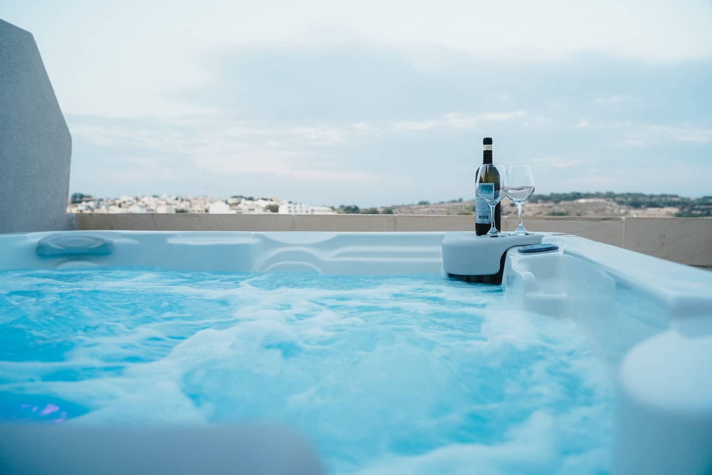 Private hot tub bubbling on the penthouse sun deck with a bottle of wine and sea views
